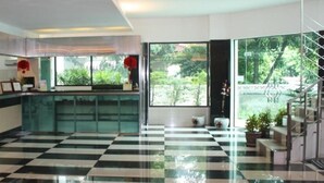A hotel lobby with a checkered floor, a reception desk, and large windows offering a view of greenery outside. - Ratchada 17 Place (Bangkok)