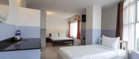 Ein Hotelzimmer mit einem Bett, einem Schreibtisch und einem Stuhl. Es gibt ein Fenster mit Vorhängen und eine Klimaanlage an der Wand.
