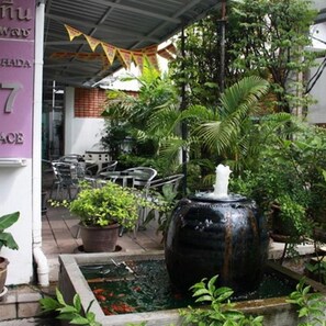 An outdoor patio area with a water feature, potted plants, and outdoor seating. - Ratchada 17 Place (Bangkok)