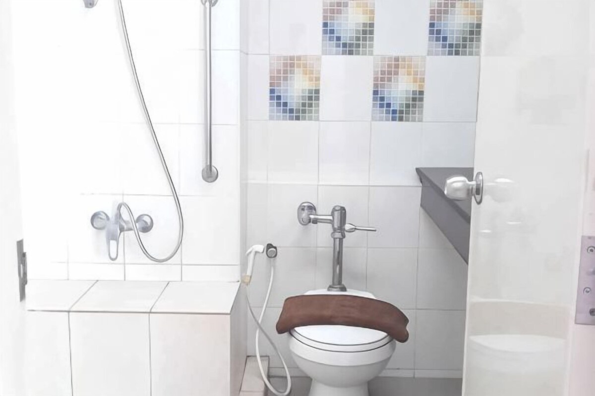 A bathroom with a toilet, shower, and tiled walls.