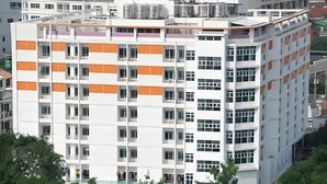 A multi-story building with a modern architectural design, featuring a mix of white and orange panels, large windows, and balconies.