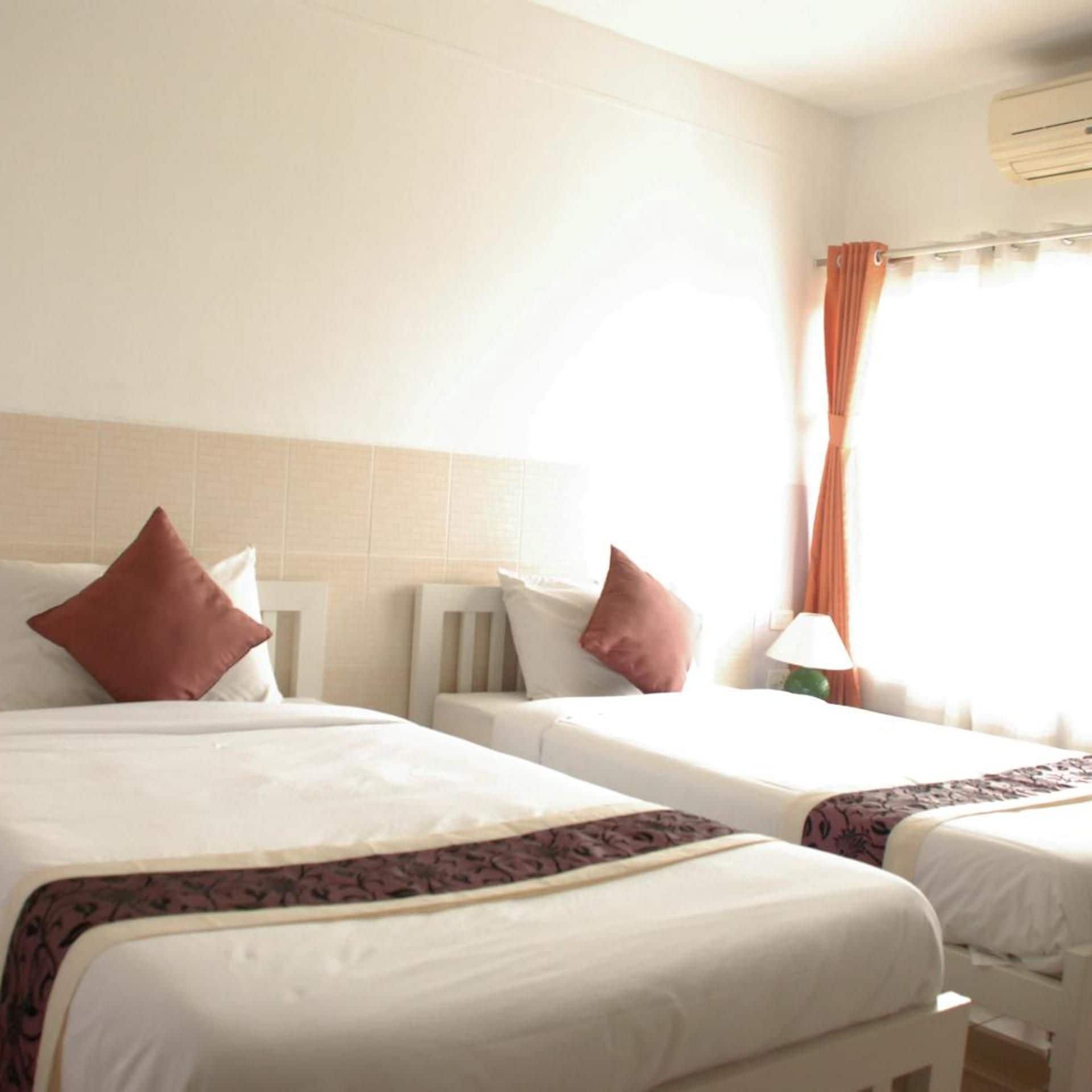 A hotel room with two beds, a nightstand, a lamp, and a window with curtains.