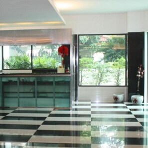 A room with a checkered floor, a window with a view of greenery, and a shelf with decorative items. - Ratchada 17 Place (Bangkok)