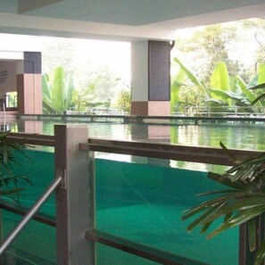 A swimming pool with a metal railing, surrounded by greenery and a view of trees. - Ratchada 17 Place (Bangkok)