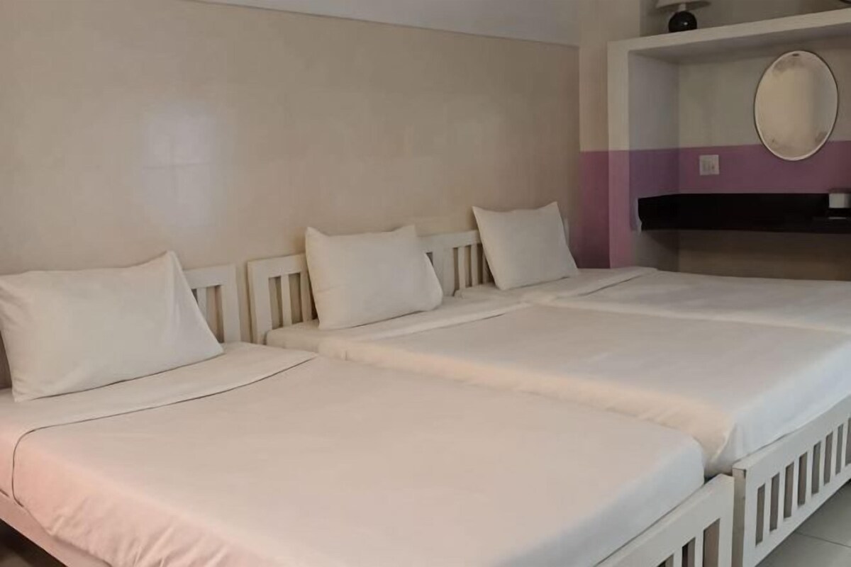 A double bed with white bedding, a bedside table, and a mirror on the wall.