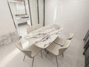 A modern dining area with a marble table and white chairs. - The May Hotel (Seoul)
