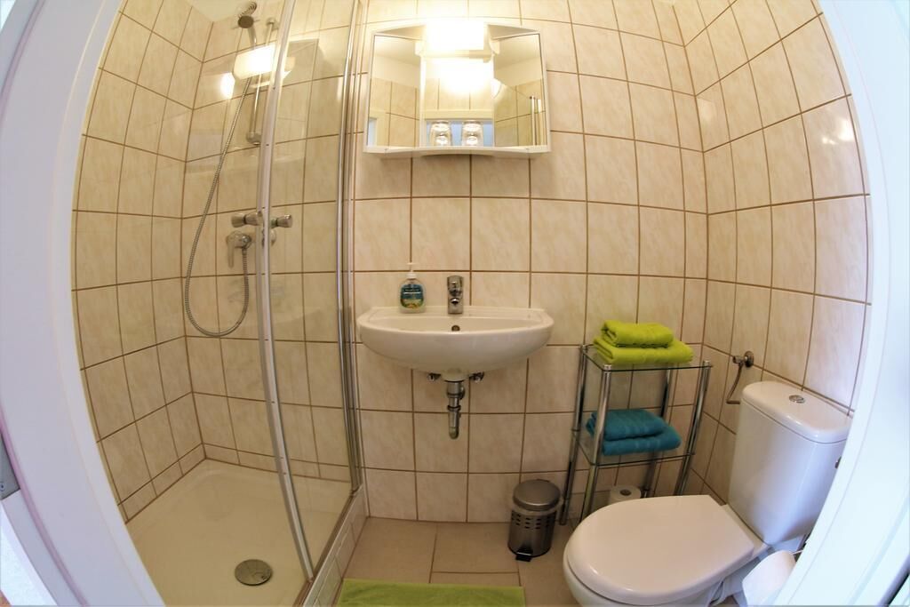 Een badkamer met douche, wastafel, toilet en spiegel.