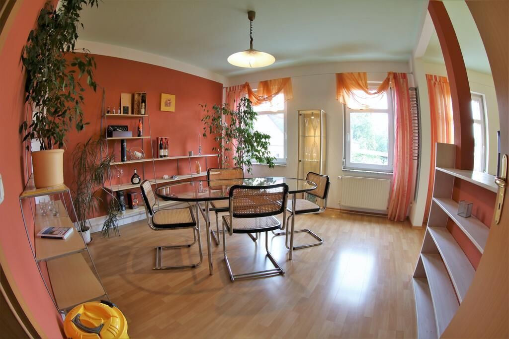 A dining area with a round table and chairs, surrounded by shelves and a radiator.