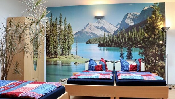 Un dormitorio con dos camas, un mural grande de un lago de montaña y una planta alta.