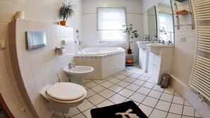 Un baño moderno con inodoro, bidé, bañera y lavamanos.
