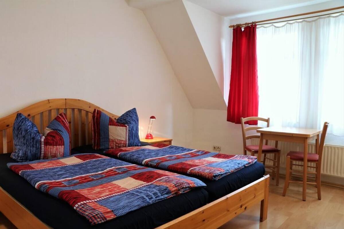 A bedroom with two beds, a desk, and a chair.