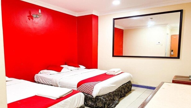 A hotel room with two beds, a large mirror, and a wooden table. - Oyo 424 Kk Inn Hotel (Ampang)