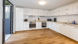 A modern kitchen with white cabinets, stainless steel appliances, and a wooden floor. - mk | monteurzimmer eschborn (Eschborn)