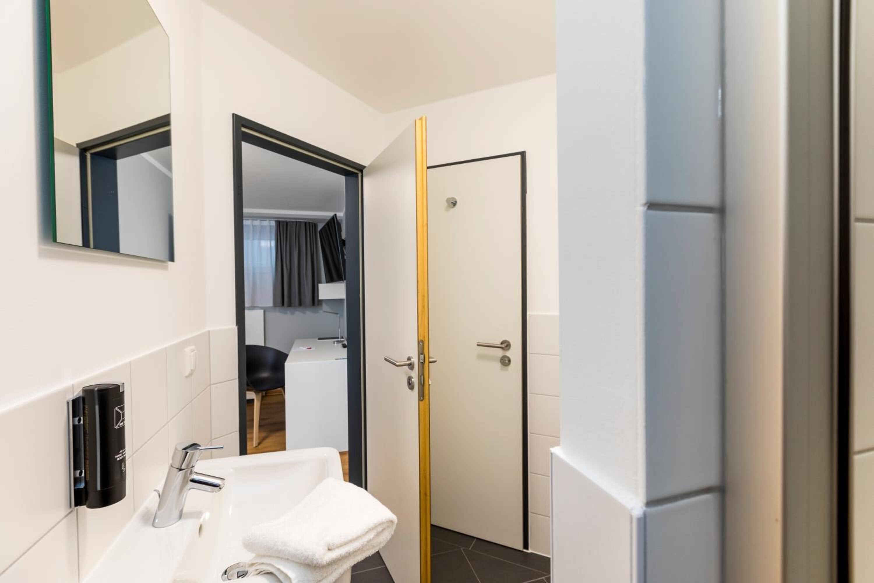 Une salle de bain moderne avec un lavabo blanc, une serviette et un miroir.