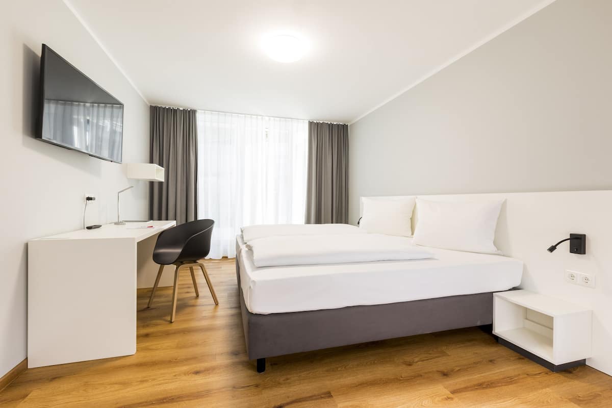 Une chambre d’hôtel moderne, équipée d’un lit, d’un bureau et d’une chaise.
