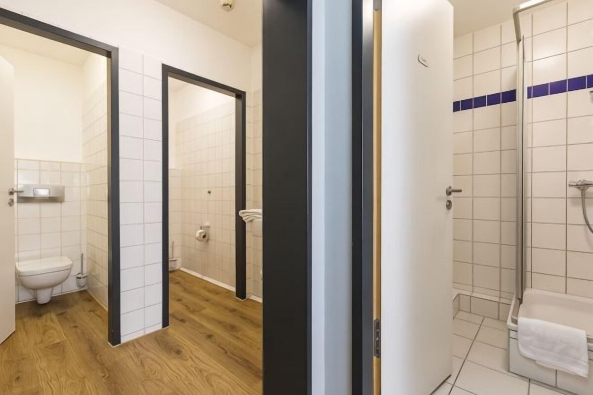 Un baño con inodoro, ducha y barra para toallas.