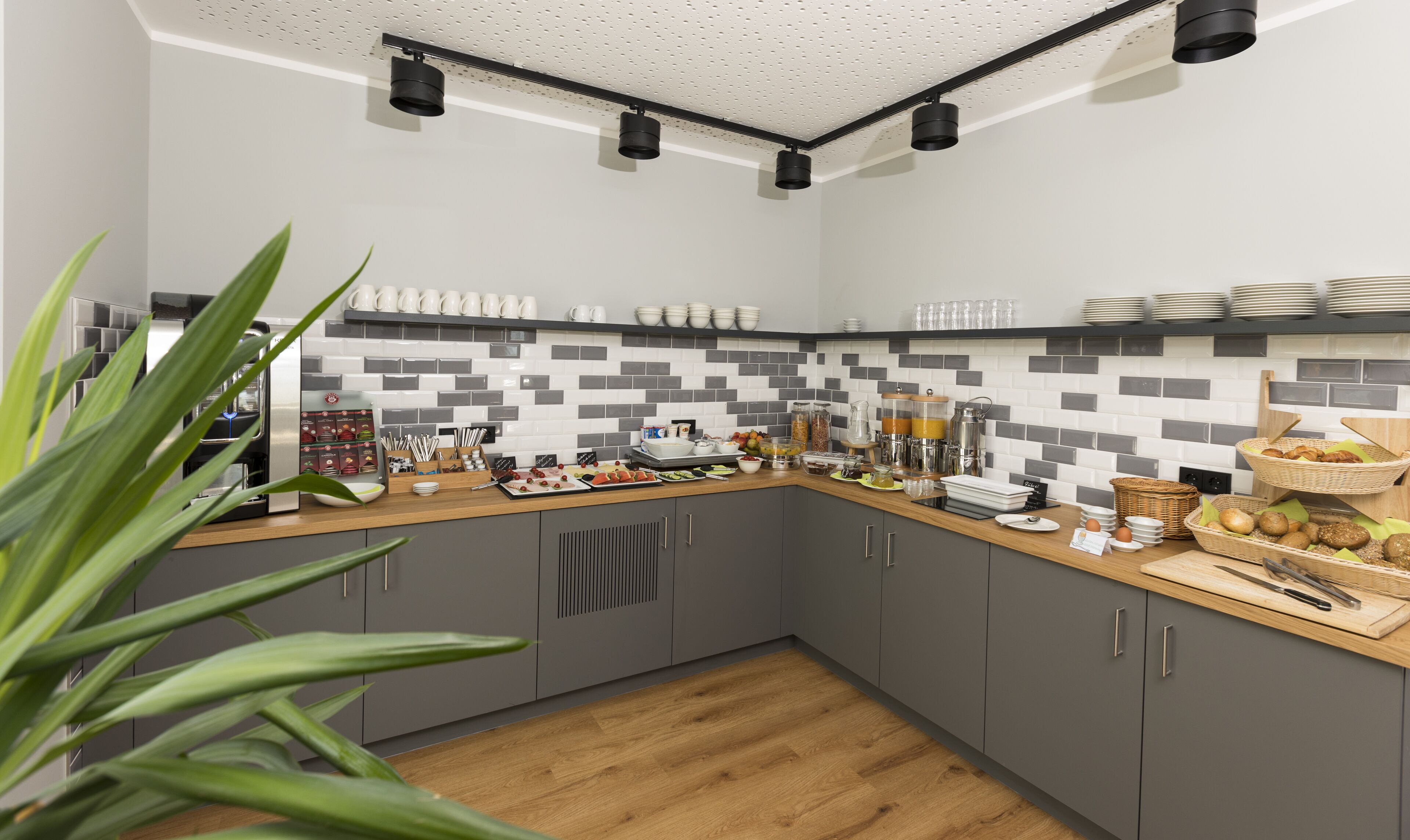 Una cocina moderna con armarios grises, encimera de madera y salpicadero de azulejos.