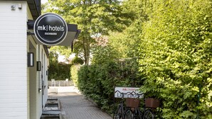 A hotel entrance with a sign reading "mk hotels ESCHBORN" and a bicycle with a basket. - mk | monteurzimmer eschborn (Eschborn)