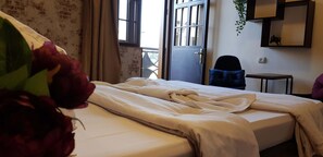 Una stanza con un letto, una sedia, un tavolino e una finestra con tende.