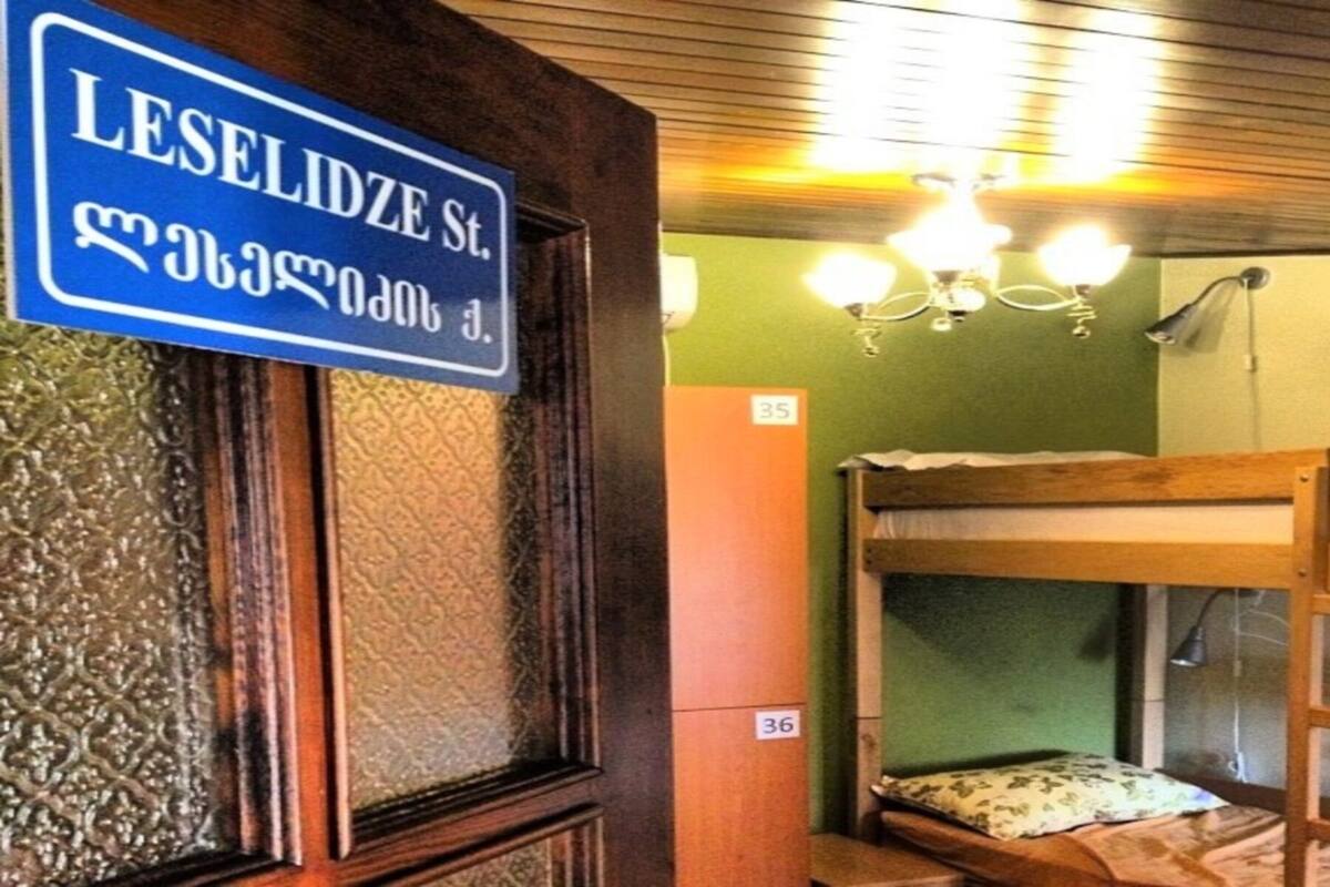 A room with a bunk bed, a wooden door, and a sign indicating 'LESELIDZE St.'