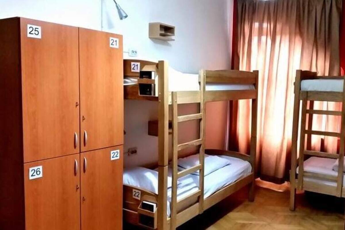 A dormitory room with bunk beds, wooden wardrobes, and a small desk.