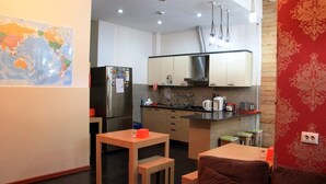 A compact kitchen with modern appliances, a dining area with a small table and two chairs, and a world map on the wall. - Envoy Hostel (Tbilisi)