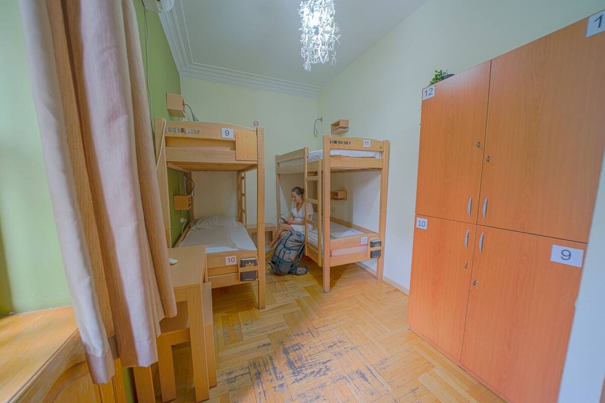 A dormitory room with bunk beds, wooden cabinets, and a chandelier.