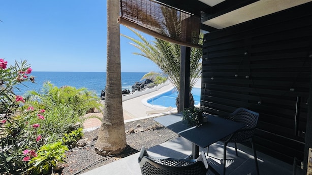 A covered outdoor area with a pool, seating, and a view of the ocean. - Ocean shore apartment 2 (Santiago del Teide)