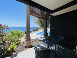 A covered outdoor area with a pool, seating, and a view of the ocean. - Ocean shore apartment 2 (Santiago del Teide)