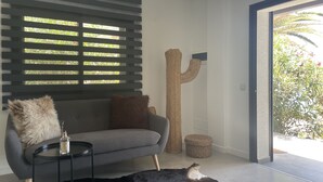A modern living room with a grey sofa, a small round table with a bottle, a fluffy pillow, a large woven sculpture, and a woven stool. - Ocean shore apartment 2 (Santiago del Teide)