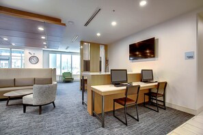 A modern office space with a desk, chairs, a sofa, and a large window. - Holiday Inn Express & Suites Calgary Airport Trail NE by IHG (Calgary)