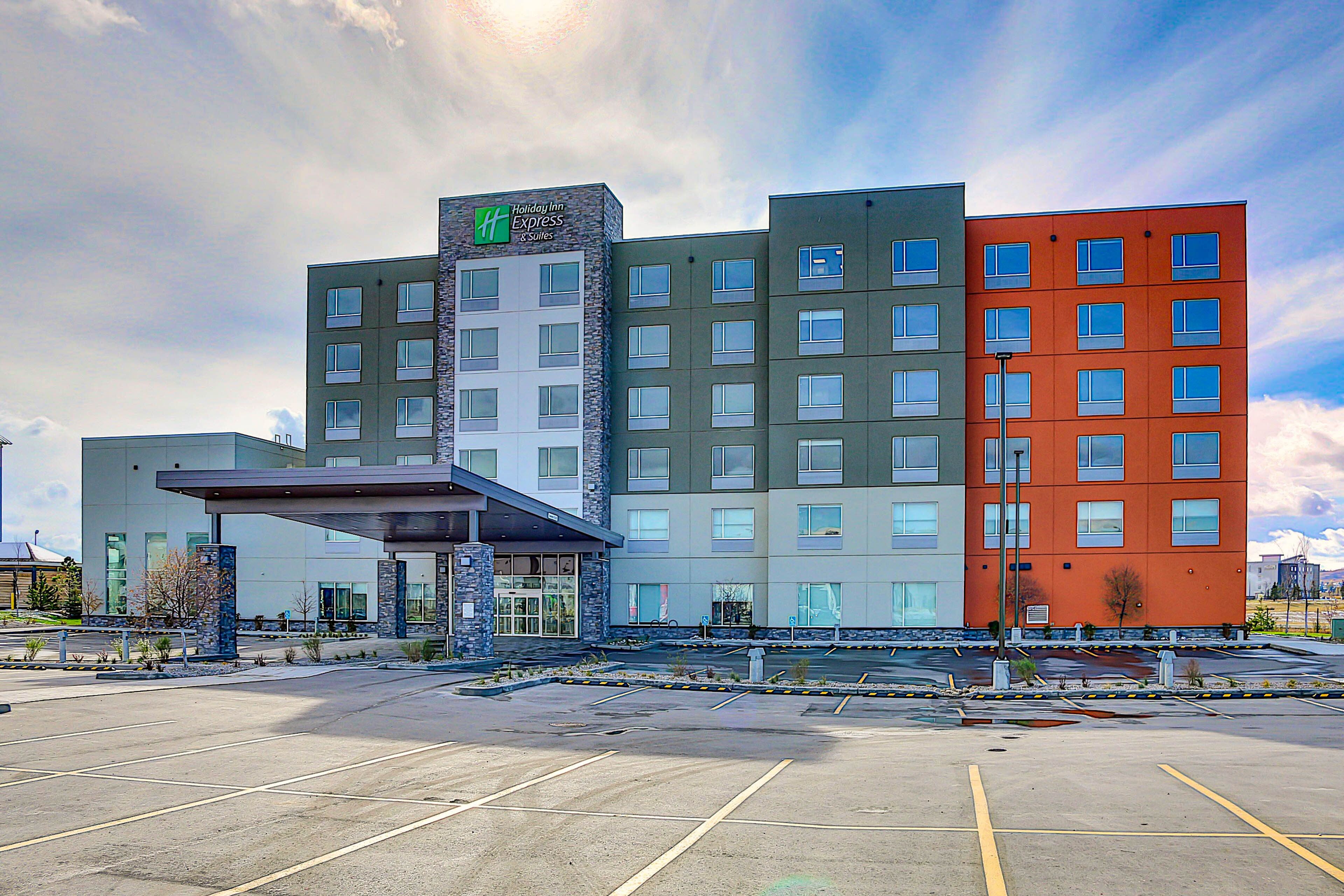 A Holiday Inn Express & Suites hotel with a modern design, featuring a stone facade and multiple windows.