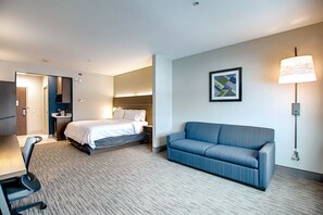 Une chambre d’hôtel avec un lit, un canapé, un bureau et une chaise.