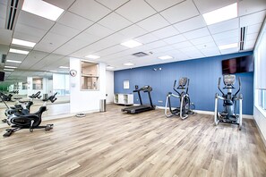 A fitness center with various exercise machines, a clock, and a mirror. - Holiday Inn Express & Suites Calgary Airport Trail NE by IHG (Calgary)