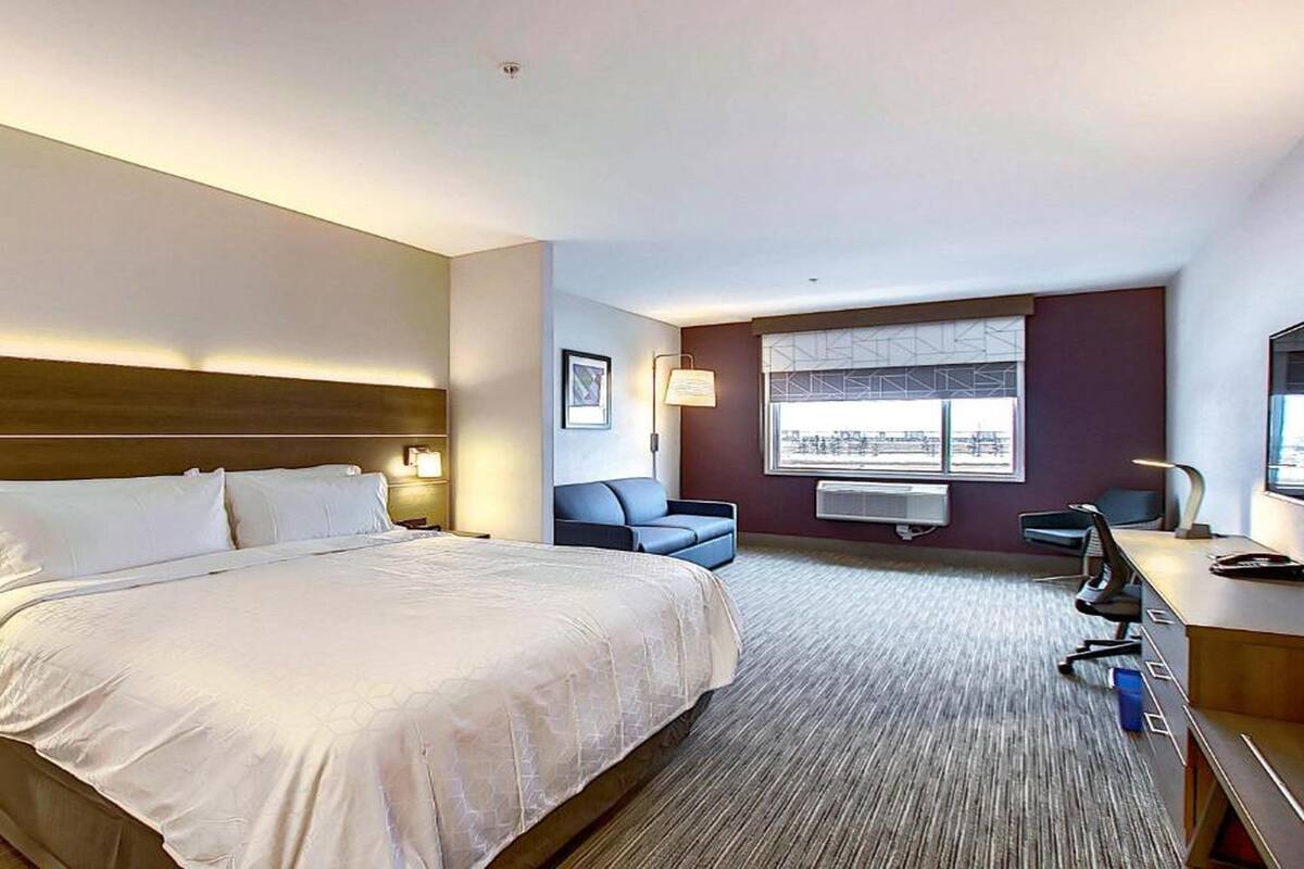A hotel room with a large bed, a desk, a chair, and a window with a view.