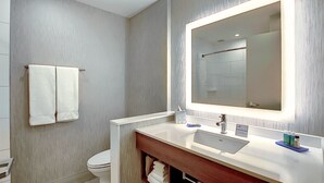 Une salle de bain moderne avec un grand miroir, un lavabo blanc et un porte-serviettes.