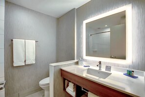 Une salle de bain moderne avec un grand miroir, un lavabo blanc et un porte-serviettes.