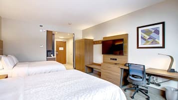 A hotel room with two beds, a desk with a computer, a TV, and a framed picture on the wall.