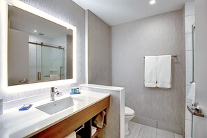 Une salle de bain moderne avec un grand miroir, un lavabo blanc et une cabine de douche en verre.