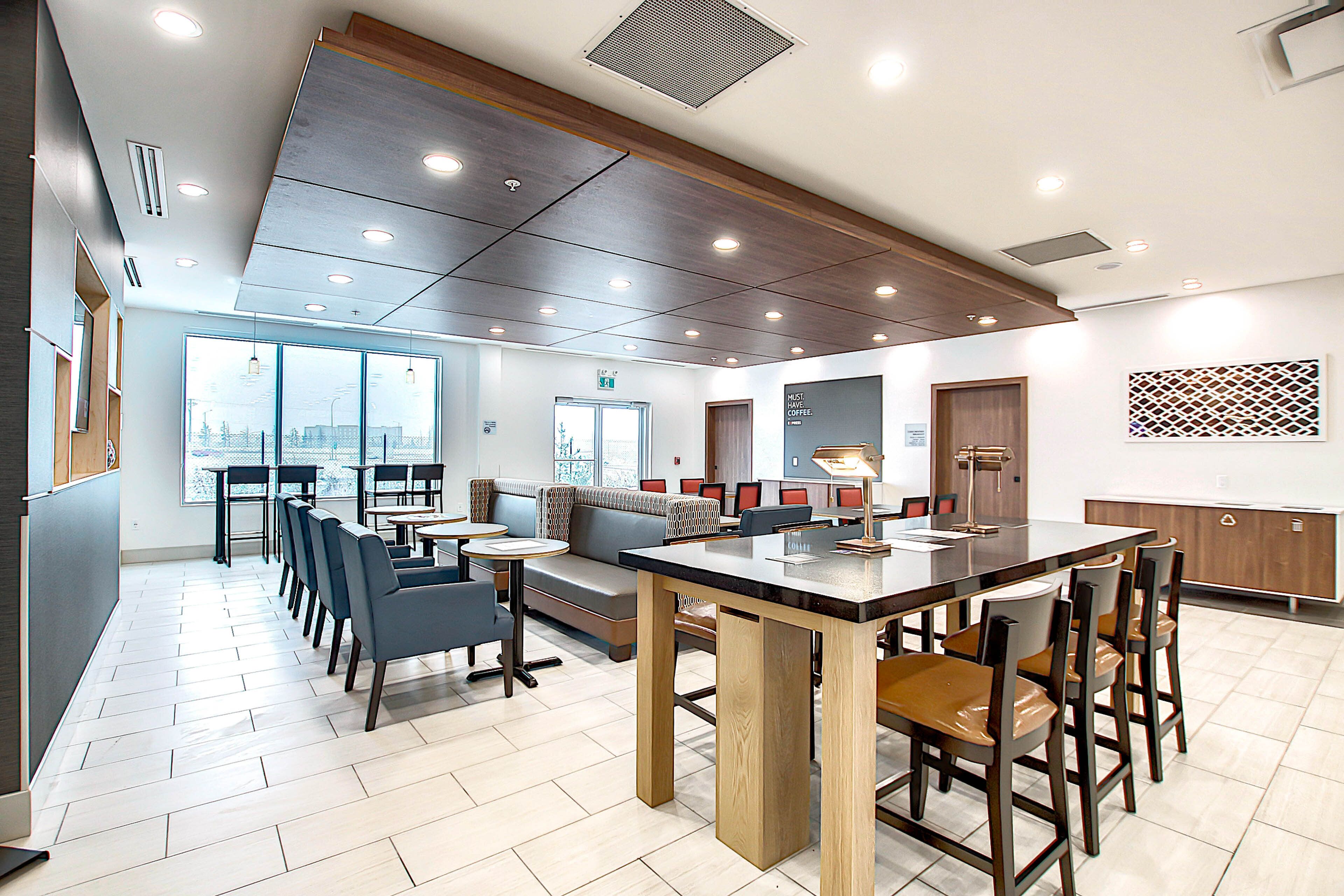 A modern interior with a central dining table, seating arrangements, and a view through large windows.