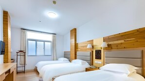 A hotel room with three beds, wooden paneling, a window with curtains, a desk, and a telephone. - Huangshan Baiyun Hotel (Huangshan)