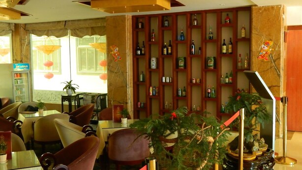 A hotel lobby with a seating area, a wall of liquor bottles, and a Christmas tree. - Huangshan Baiyun Hotel (Huangshan)
