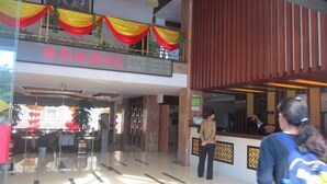 A hotel lobby with a reception desk, a glass entrance, and a sign with prices in Chinese. - Huangshan Baiyun Hotel (Huangshan)