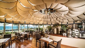 A restaurant with a view of the sea, wooden tables and chairs, and a counter with a coffee machine. - Radisson Hotel Istanbul Sultanahmet (Istanbul)