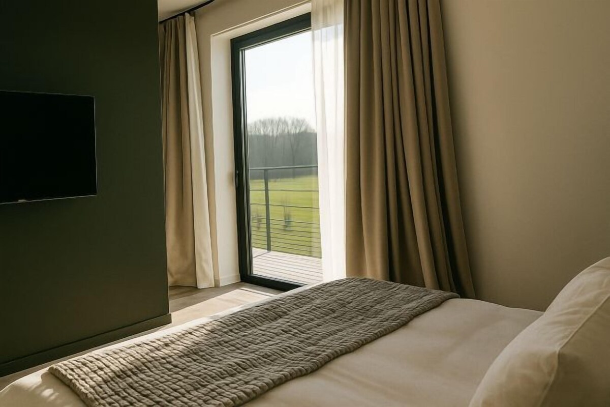 Une chambre à coucher avec un lit, une fenêtre avec des rideaux et une vue sur un paysage verdoyant.