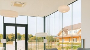 A modern interior with large windows, a round table, and grey upholstered chairs. - Off Meeting Wavre Hotel (Wavre)