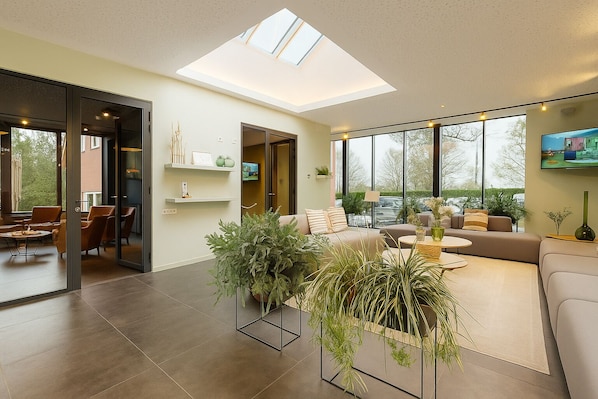 Una sala de estar moderna con tragaluces, ventanas amplias y un espacio de estar acogedor.
