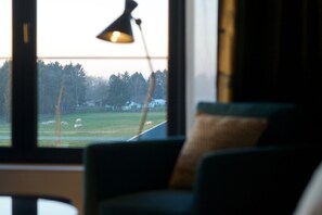 Enjoy a peaceful view of the surrounding countryside from this room's large window, featuring a grassy field with grazing sheep.