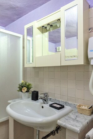A bathroom with a white sink, a mirror, and a white cabinet above the sink. - Il Portico Della Rocca (Castellina in Chianti)
