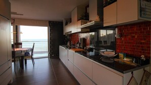 Una cuina moderna amb una illa gran, zona de menjador amb vistes i un frontissos de rajola vermella.